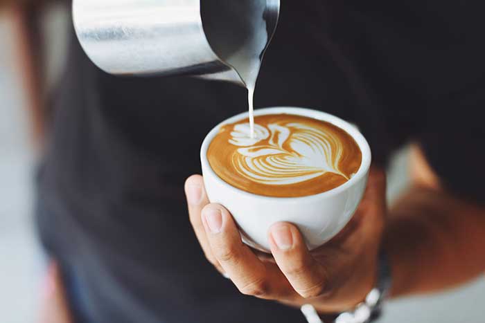 barista pouring cream into a latte